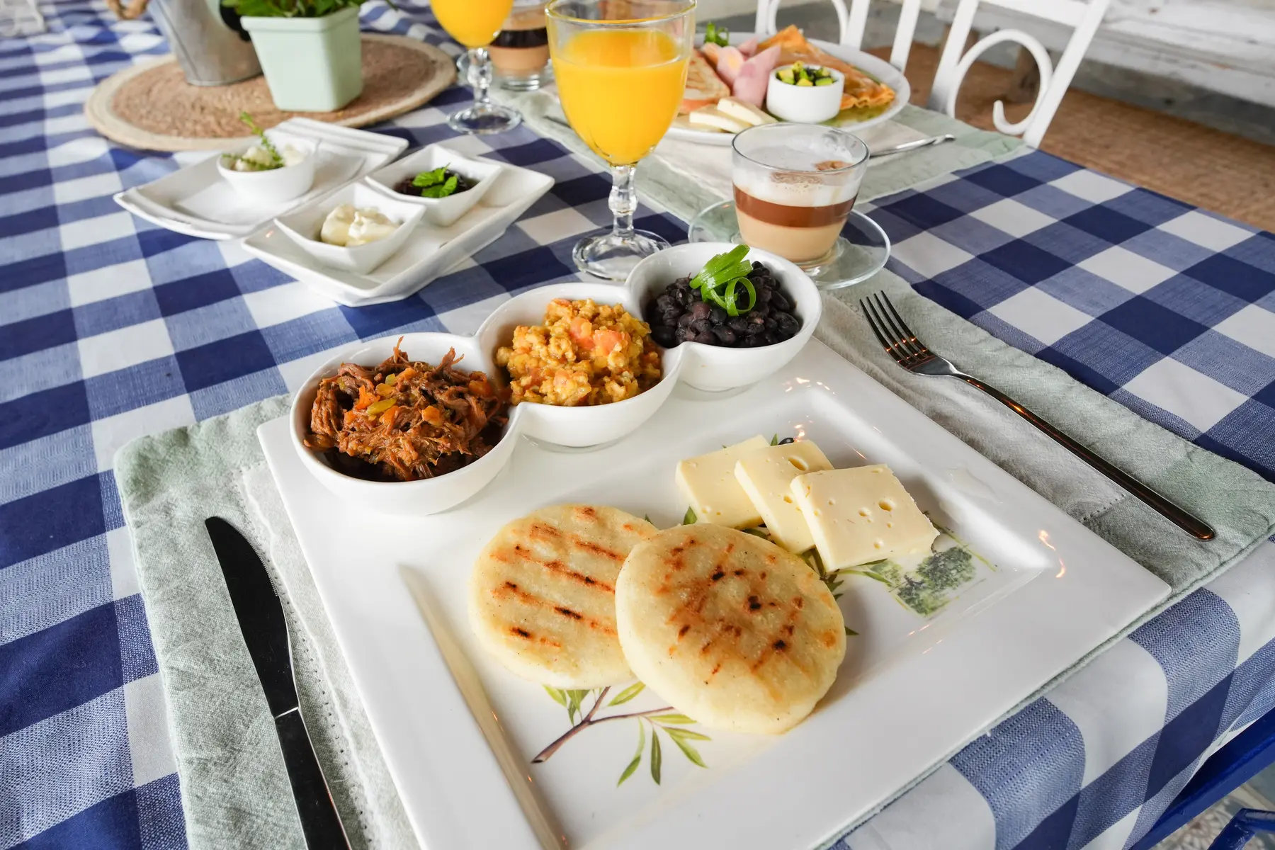 Desayuno venezolano con arepa, queso y acompañantes servido en el jardín